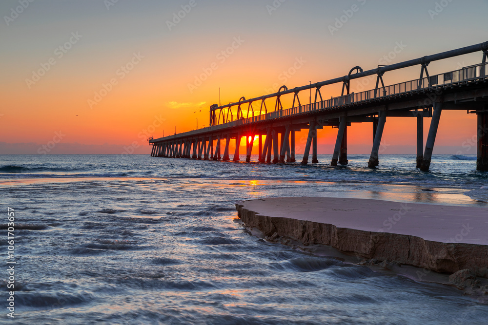 Golden sunrise sky and beach sand at the Southport Spit jetty. Gold Coast, Australia Golden sunrise sky and beach sand at the Southport Spit jetty. Gold Coast, Australia