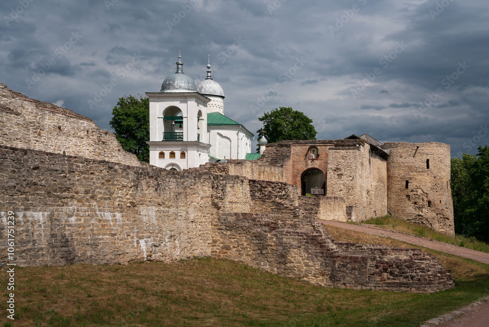 View of the wall of the Izborsk fortress, the Nikolsky Gate and St. Nicholas (Nikolsky) Cathedral (XIV-XVII century) on a sunny summer day, Izborsk, Pskov region, Russia View of the wall of the Izborsk fortress, the Nikolsky Gate and St. Nicholas (Nikolsky) Cathedral (XIV-XVII century) on a sunny summer day, Izborsk, Pskov region, Russia