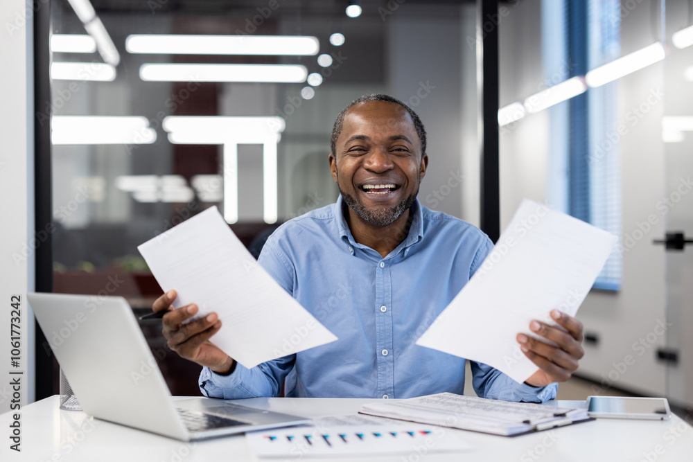 Mature african american businessman smiling confidently, holding papers in a modern office setting. Represents success, positivity, and professionalism in workplace environment. Mature african american businessman smiling confidently, holding papers in a modern office setting. Represents success, positivity, and professionalism in workplace environment.