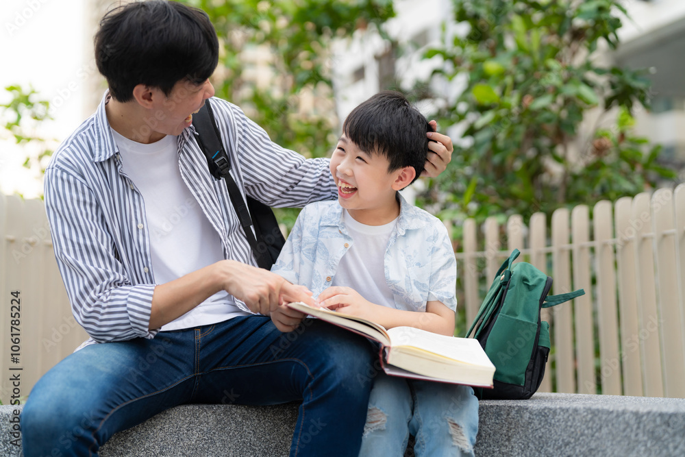 In a vibrant garden, a happy boy reads a book with his father. Their cheerful smiles capture the essence of family, fun, and learning during a beautiful summer day outdoors. In a vibrant garden, a happy boy reads a book with his father. Their cheerful smiles capture the essence of family, fun, and learning during a beautiful summer day outdoors.