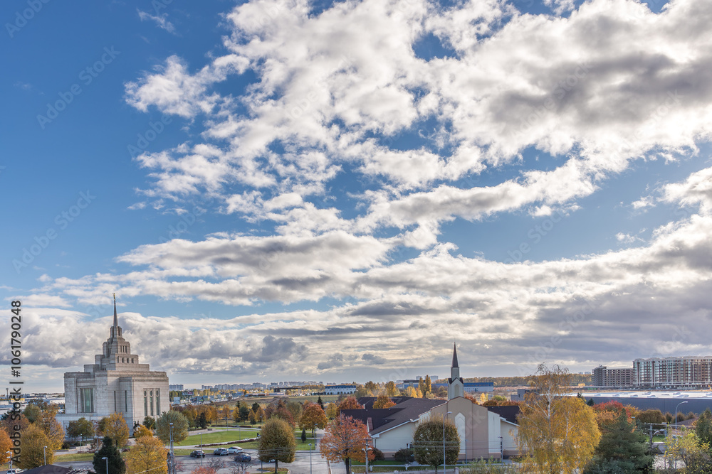 Fototapeta premium Mormon Temple in Kyiv. White stone temple. Panorama of an autumn European city. Well-groomed city park on a sunny day. Sights of Ukraine. Tourism in Ukraine. High blue sky. 