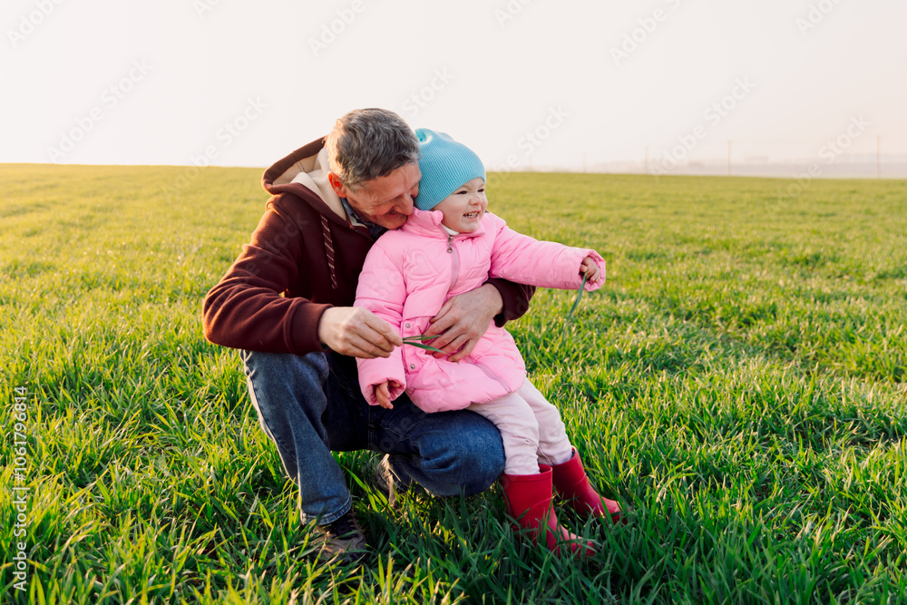 Happy grandfather with smiling granddaughter on field with sunshine Happy grandfather with smiling granddaughter on field with sunshine
