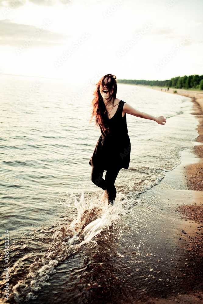 Fototapeta premium Woman Joyfully Running on the Beach at Sunset