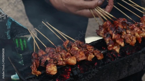 close-up of hands grilling chicken satay on a charcoal grill, indonesian culinary, indonesian food