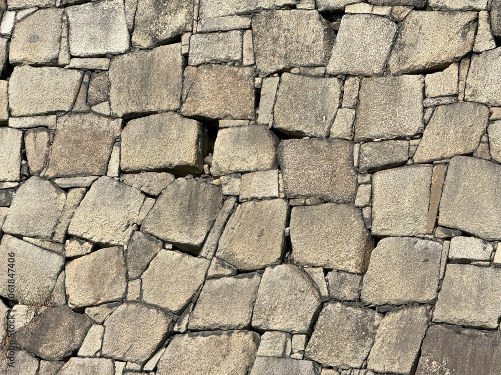 Close-up view of an ancient stone wall showcasing the texture and intricate masonry patterns Close-up view of an ancient stone wall showcasing the texture and intricate masonry patterns