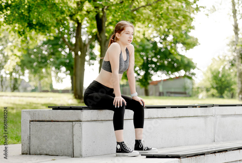 Sporty Girl Catches Her Breath On A Bench After Running In The Park