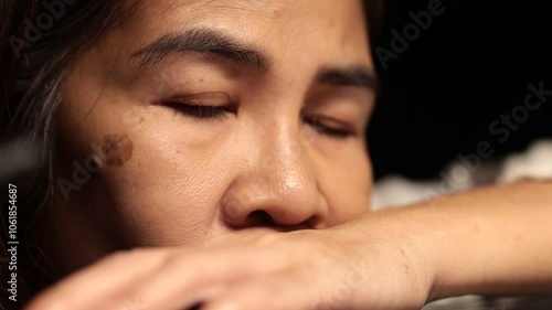 A close-up of a woman with a sad expression, woman resting with eyes closed, appearing relaxed and calm in a peaceful moment.
