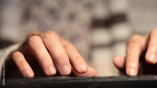 Close-up of hands typing on a key board, showing detailed interaction with the device, set against a blurred background