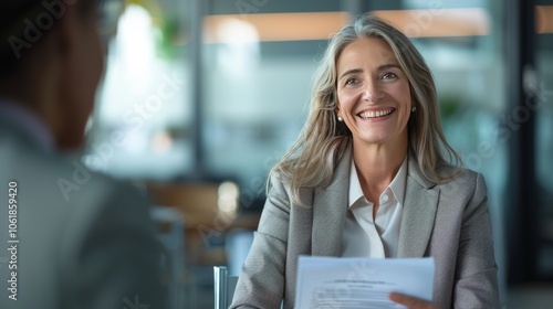 Fototapeta Naklejka Na Ścianę i Meble -  Smiling mature business woman hr holding cv document at job interview. Happy mid aged professional banking manager or lawyer consulting client sitting at workplace in corporate office meeting.