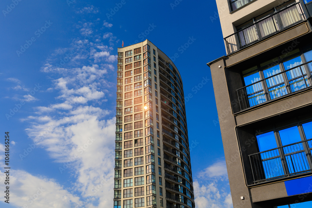 Fototapeta premium Modern buildings, walls and windows, reflections and sun rays. City view on a sunny day. 