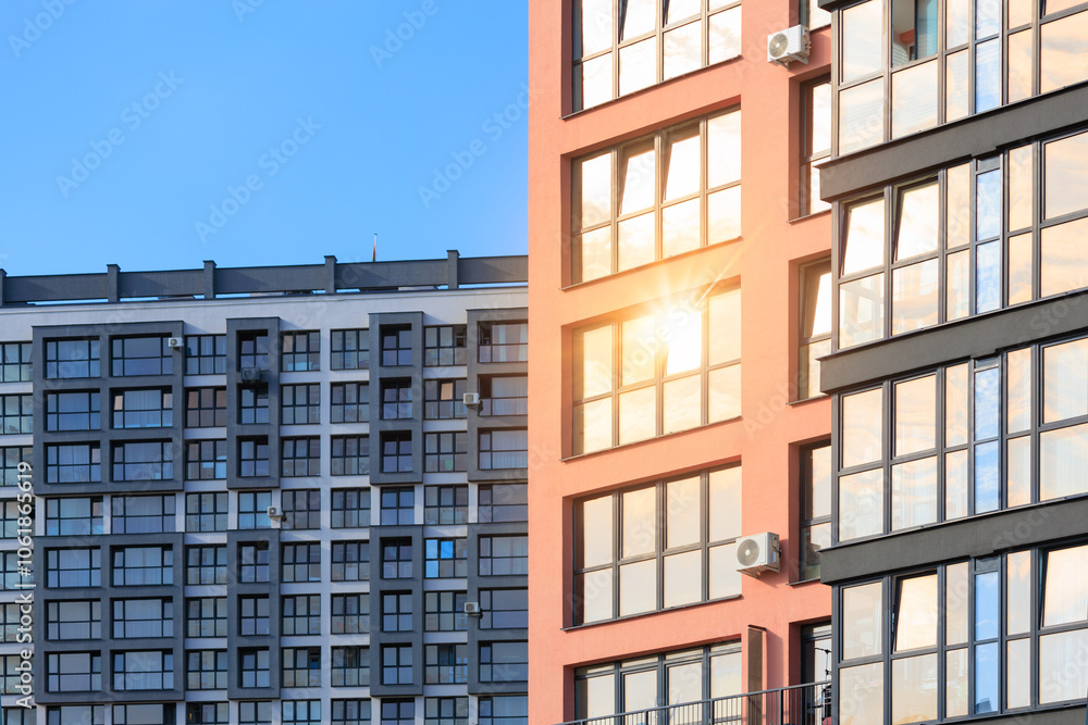 Obraz premium Modern buildings, walls and windows, reflections and sun rays. City view on a sunny day.