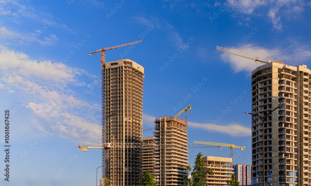 Fototapeta premium Construction cranes and new buildings, construction work of modern skyscrapers on a sunny day.