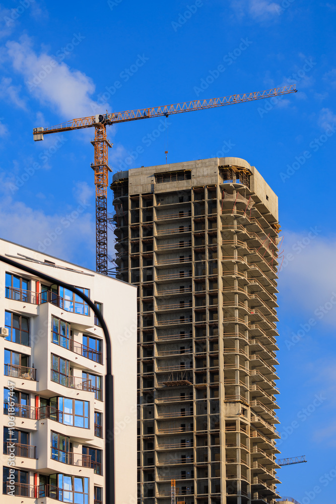 Fototapeta premium Construction cranes and new buildings, construction work of modern skyscrapers on a sunny day.