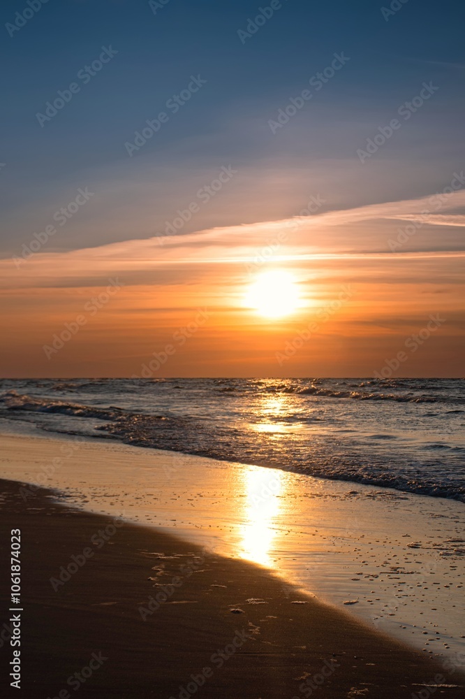 Sandy beach with the sun in the background. Beautiful sunset over the Baltic Sea in Gdynia, Poland.