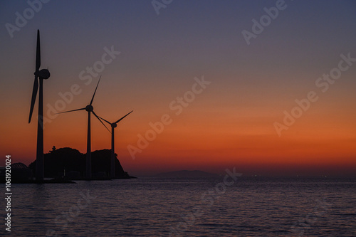 on the beach with a wind turbine and an island in the background taken at the tando island port of Korea. photo