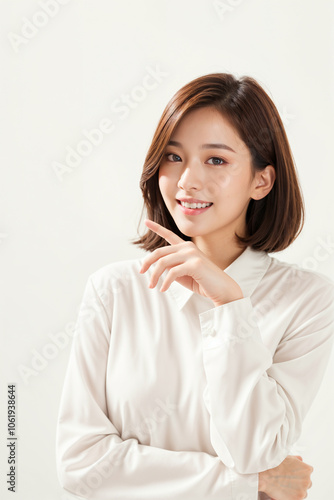 A woman with a white shirt and brown hair is smiling and pointing her finger