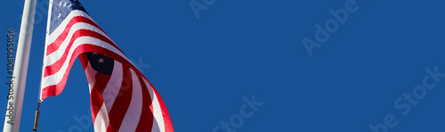 American flag blowing in the wind on the blue sky background