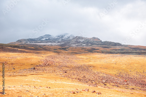 Rugged mountain landscape with golden tundra and cloudy sky