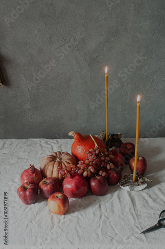 Autumn still life harvest Thanksgiving table serving with pumpkins pommegranates and grapes on linen cloth with candles modern minimalist scandinavian sustainable eco styling