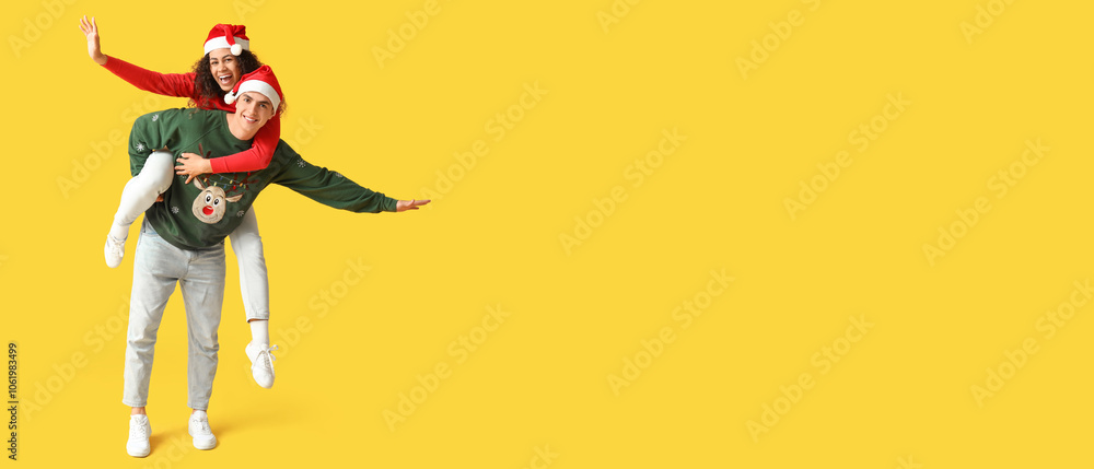 Happy young couple in Christmas sweaters having fun on yellow background Happy young couple in Christmas sweaters having fun on yellow background