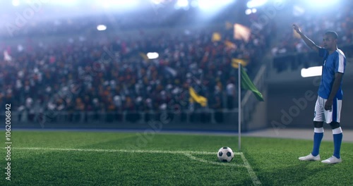 A football player in a blue jersey takes a corner kick during an intense match in a packed stadium. The lively crowd cheers under bright stadium lights, capturing the energy and excitement of the game