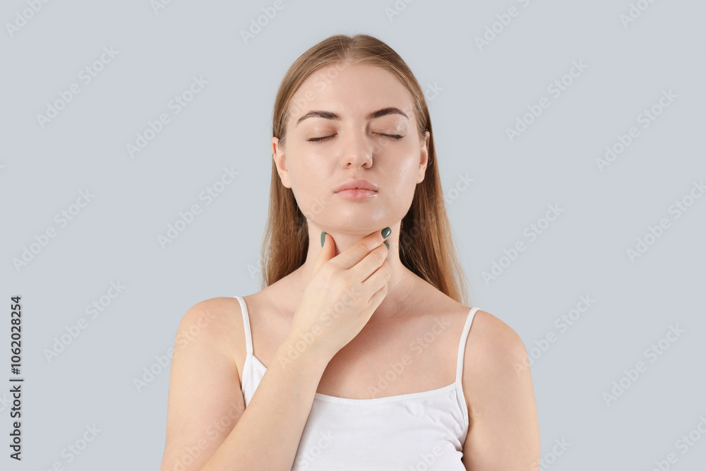 Young woman self-examining thyroid gland on grey background, closeup Young woman self-examining thyroid gland on grey background, closeup