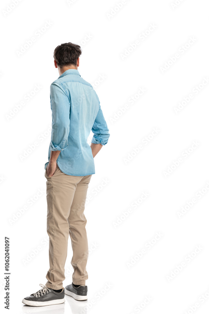 back view of casual guy in blue denim shirt holding hands in pockets back view of casual guy in blue denim shirt holding hands in pockets