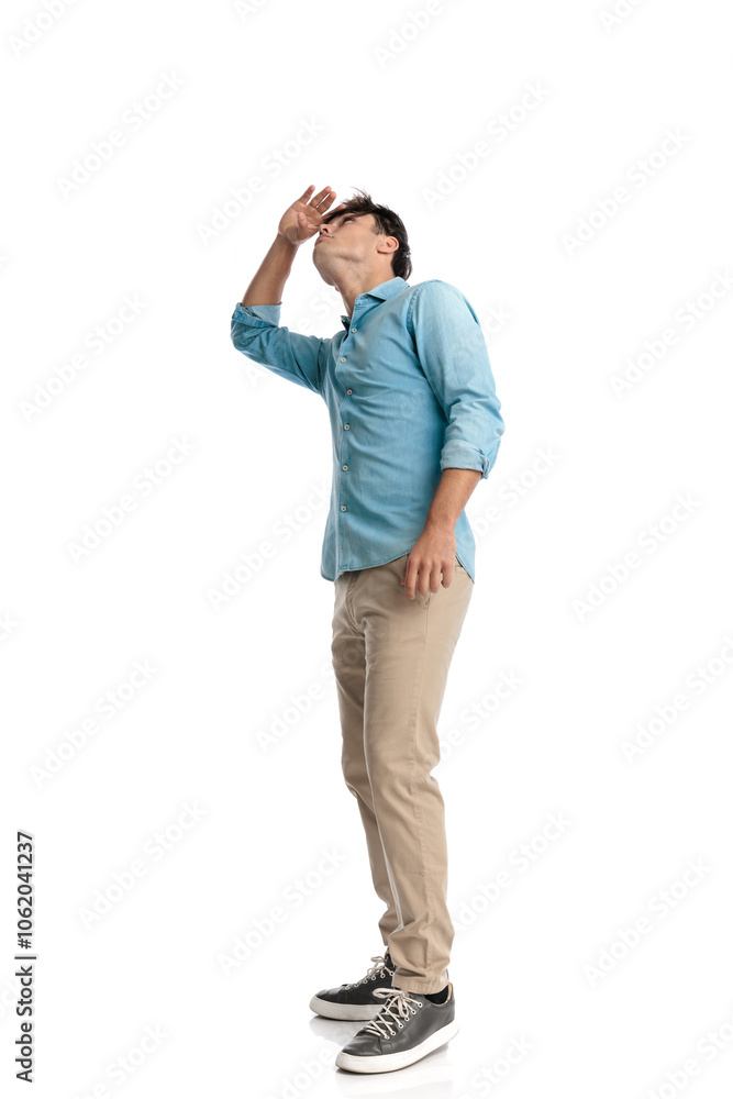 curious young student holding hand to forehead and looking far away curious young student holding hand to forehead and looking far away