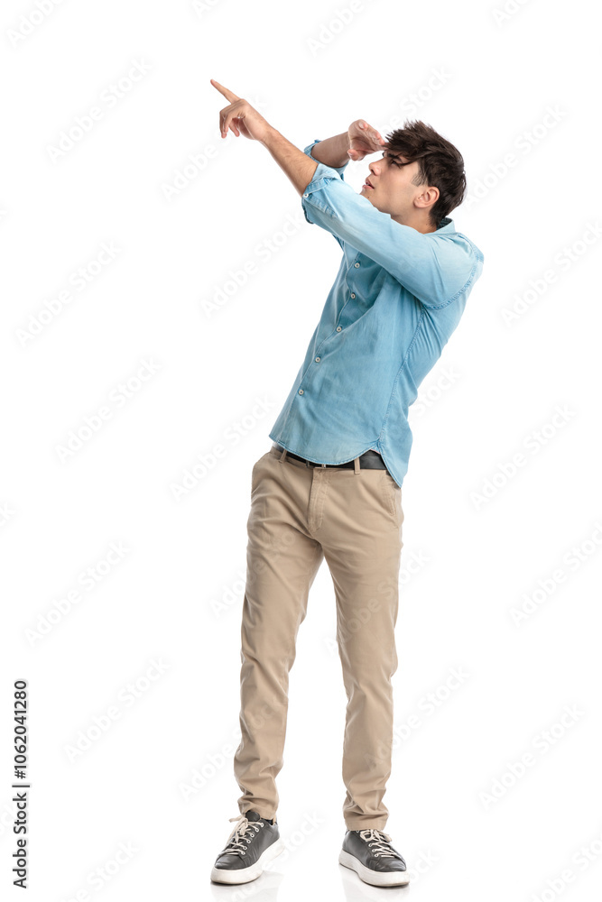 young student with hand to forehead pointing finger to the sky far away young student with hand to forehead pointing finger to the sky far away