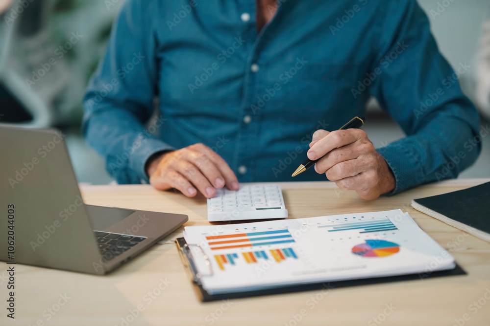Businessman is working with financial charts and using calculator for data analysis in office Businessman is working with financial charts and using calculator for data analysis in office