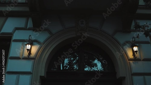 old street lamps hanging on wires against the backdrop of a building facade with columns and a large thermal window In the evening