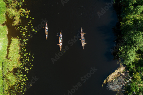 An aerial of a group of dugout canoes moving on a river during a summer day in rural Estonia, Northern Europe photo