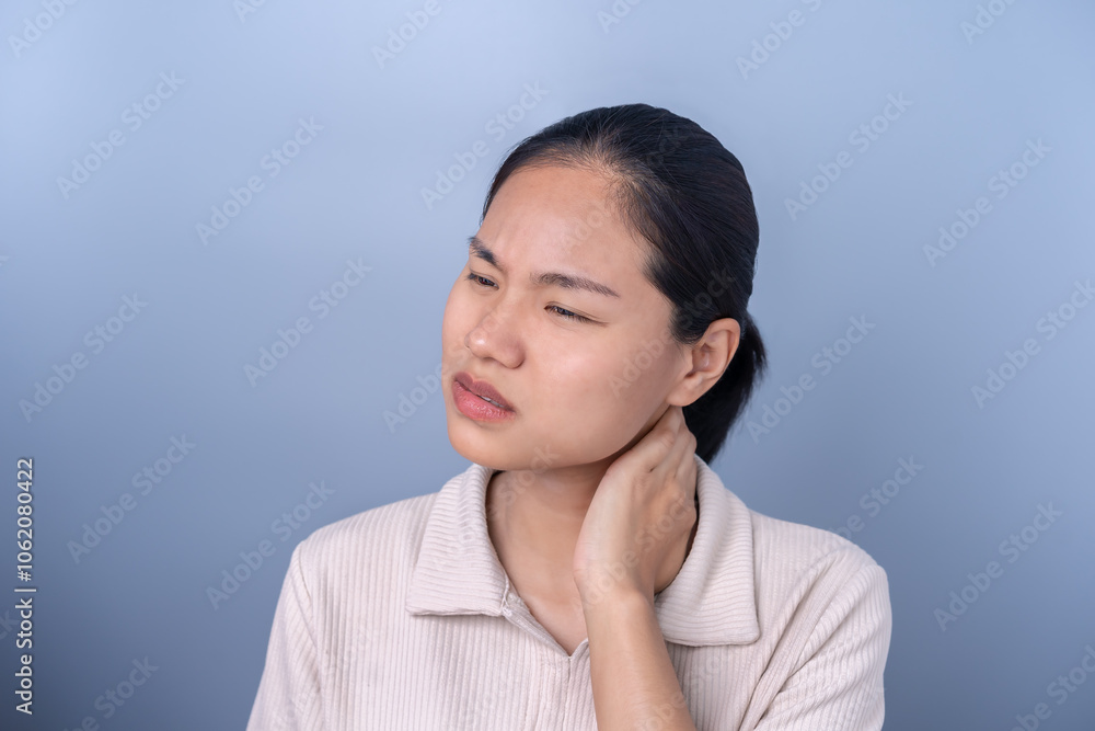 Woman holds her neck with a pained expression on her face. There may be neck pain or discomfort. This is due to muscle strain, tight neck, and shoulders, or office syndrome. Woman holds her neck with a pained expression on her face. There may be neck pain or discomfort. This is due to muscle strain, tight neck, and shoulders, or office syndrome.