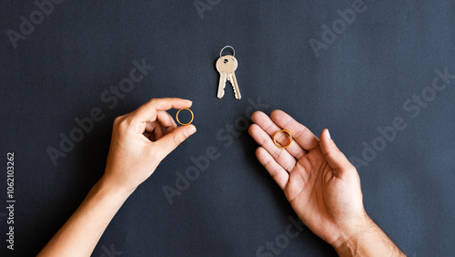 Male and female hands with wedding rings, keys, couple on dark background. Concept of divorce or marrige