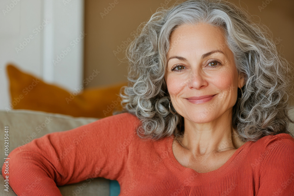 A smiling elderly woman with curly hair sits comfortably at home A smiling elderly woman with curly hair sits comfortably at home