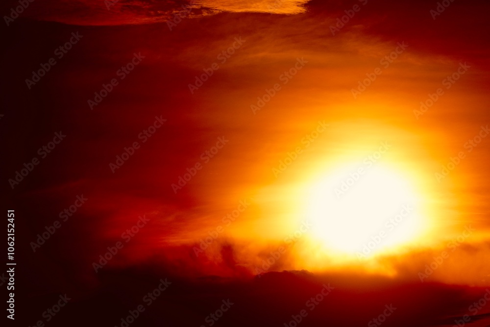Obraz premium This is a beautiful sunset or sunrise photo with bright orange, yellow, and red as the main colors in the sky. The sun is partially obscured by clouds, which makes the sky look brighter and warmer.