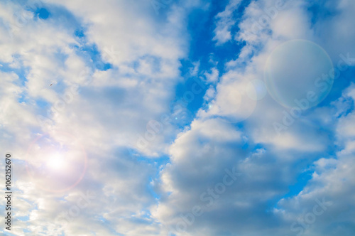 Blue sky background, white dramatic fluffy clouds lit by sunset light. Vast sky landscape scene, blue sky view