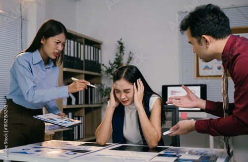 Business colleagues arguing and blaming stressed businesswoman during a late night meeting in office, concept of mobbing, stress at work and bad work environment photo