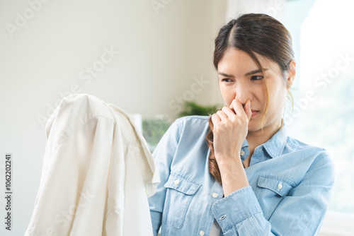 Fotografia Asian young housewife woman having bad smelling clothes hand holding breath nose