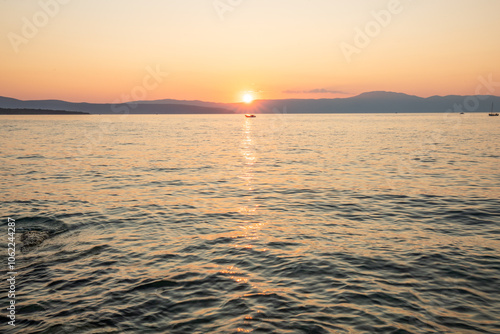 Coast, stone fortification of a harbor with a view of the sunset. Landscape shot from the sea on Krk, Croatia photo