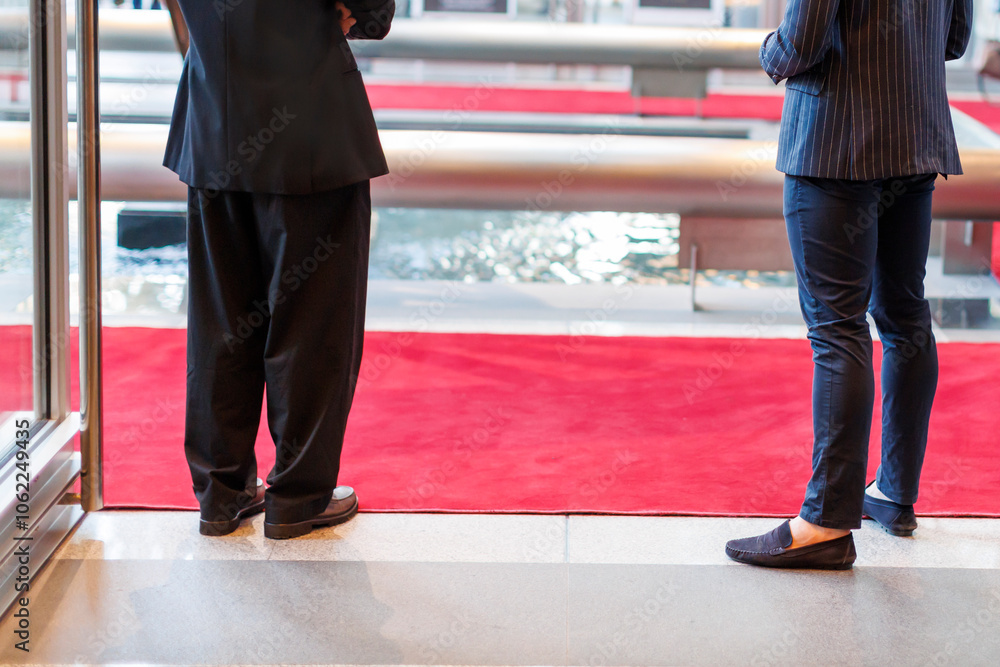 Fototapeta premium Two individuals standing on a red carpet near a fountain in a luxurious venue during a formal event