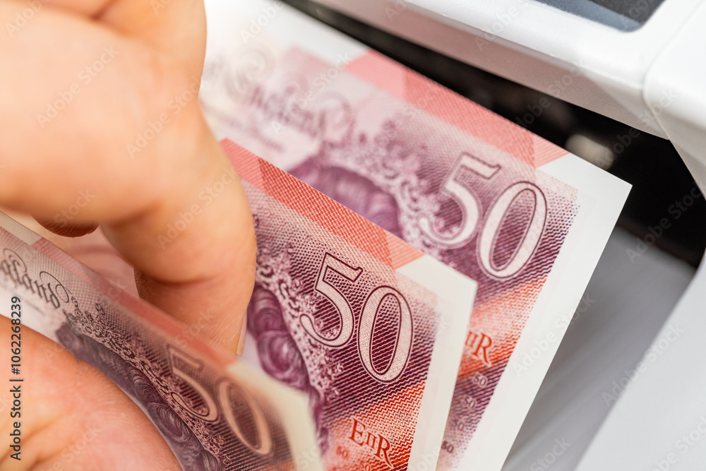 Great Britain money. British pounds in cash counting machine. Business and finance concept, Exchange rate, financial calculations, close up