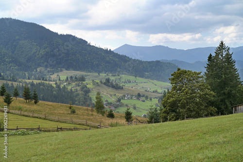 Mountain landscape with village and a green pasture in the foreground.