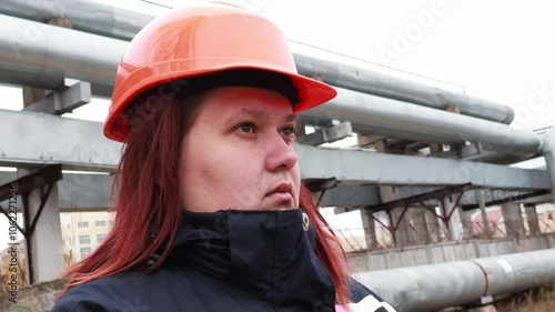 Portrait of a female industrialist against the background of an industrial view of a factory. A woman in a helmet in close-up. 4K photo