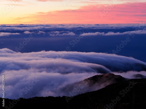 A breathtaking view of the vast sky moments after sunset, with rolling clouds gently covering the hills in a mesmerizing dance of light and colors - Pico do Arieiro, Madeira, Portugal.