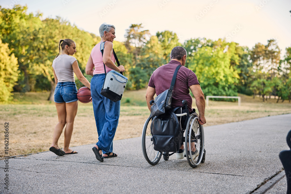 Family Enjoying Leisurely Walk in Park with Wheelchair User Family Enjoying Leisurely Walk in Park with Wheelchair User