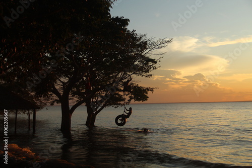 silhueta de crianças não identificadas brincando no rio tapajós, em belterra, pará  photo