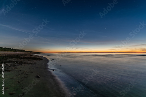 Baltic sea beach in Latvia at Autumn after sunset, stars and Comet C 2023 A3 Tsuchinshan–ATLAS far away in the sky.