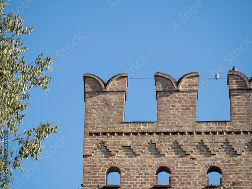 Photography Medieval brick wall with merlons reaching for the blue sky in Busseto, Parma, It