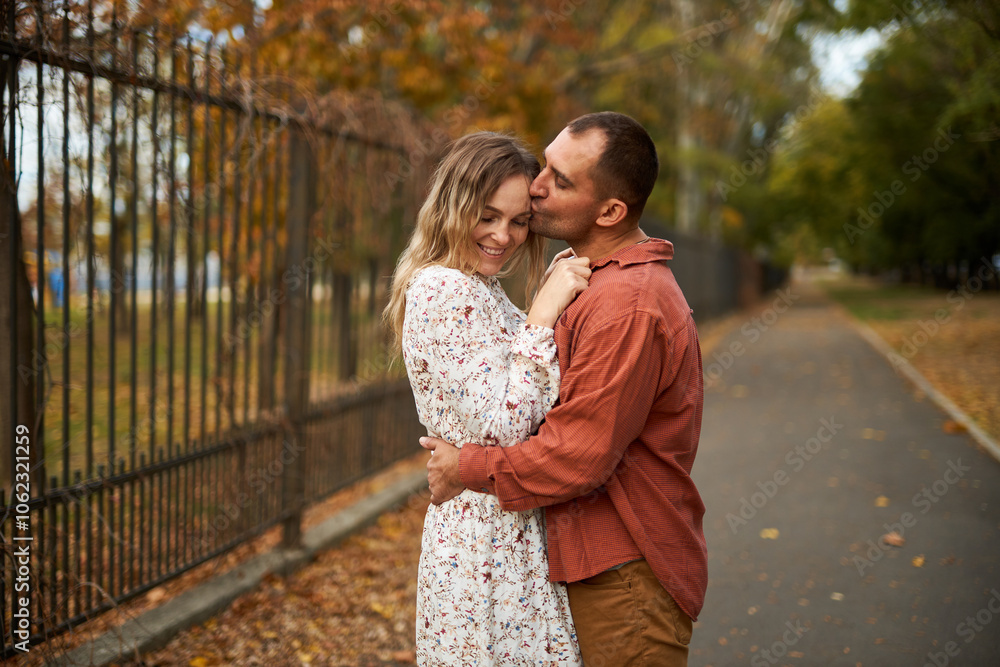 Fototapeta premium Beautiful and happy couple hugging and smiling while enjoying their time in Autumn Park